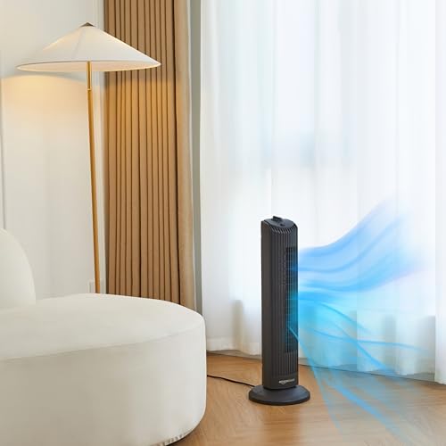 Black oscillating tower fan with remote providing cool air in modern living room by window