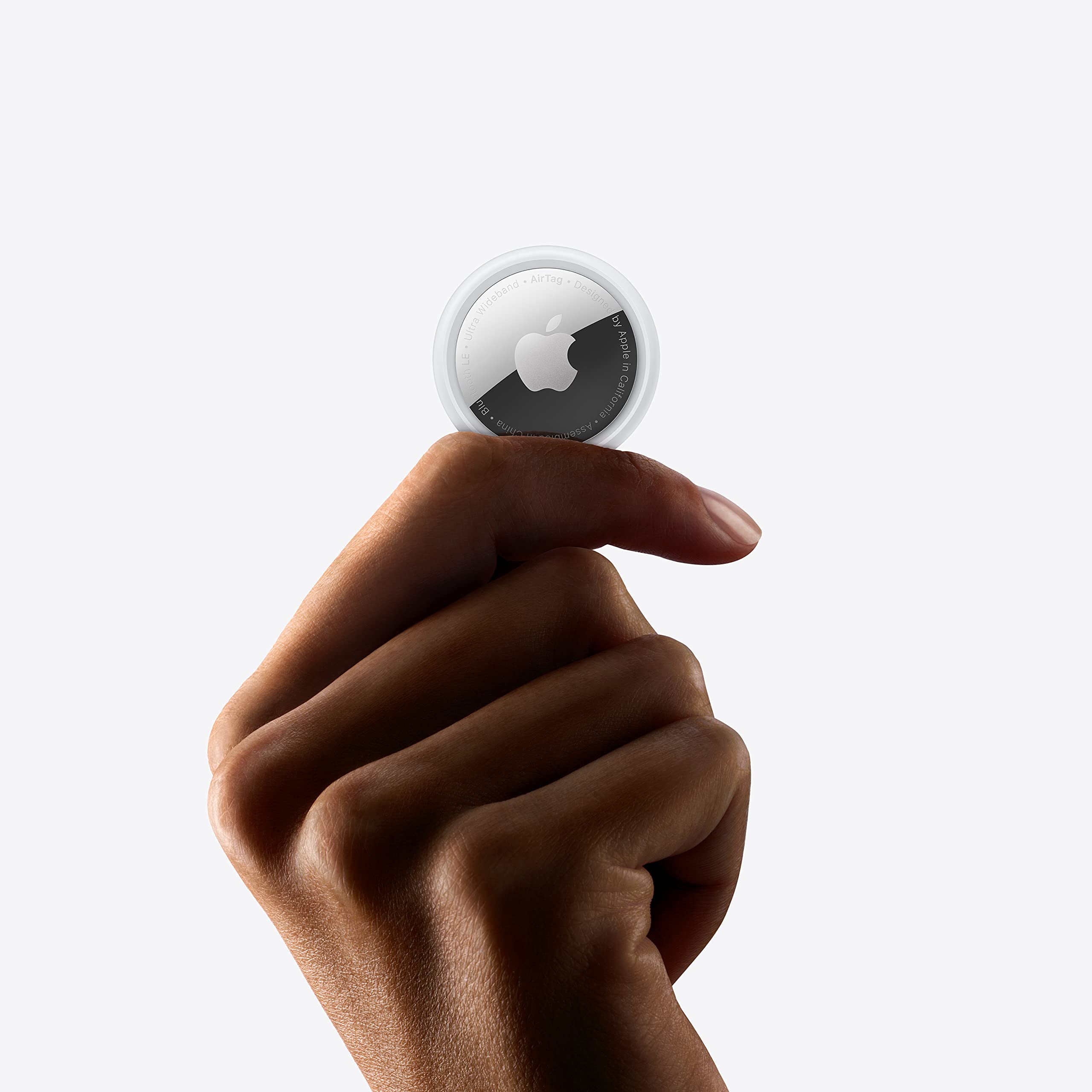 Hand holding an Apple AirTag single pack with white and silver design against a white background