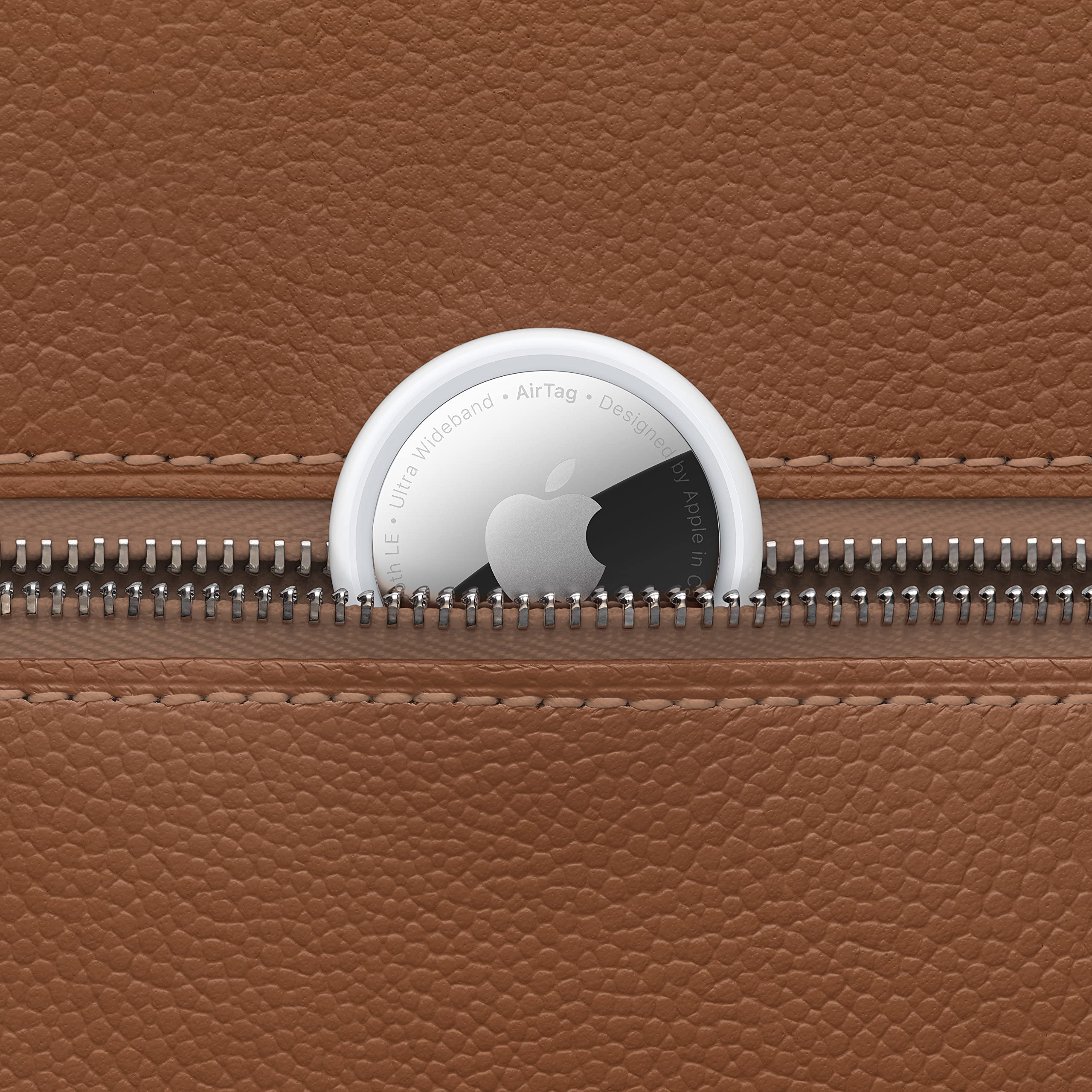 Apple AirTag single pack placed partially inside the brown leather zipper pocket