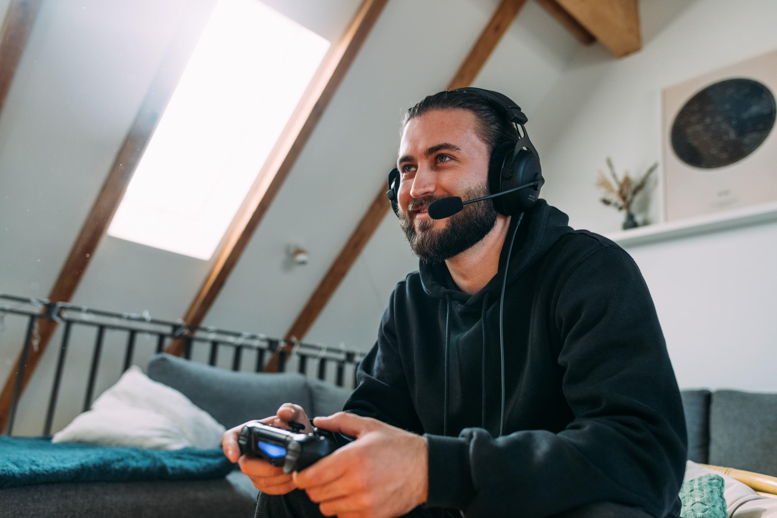 Man wearing beyerdynamic MMX 300 PRO gaming headset playing video games with a controller in a cozy living room