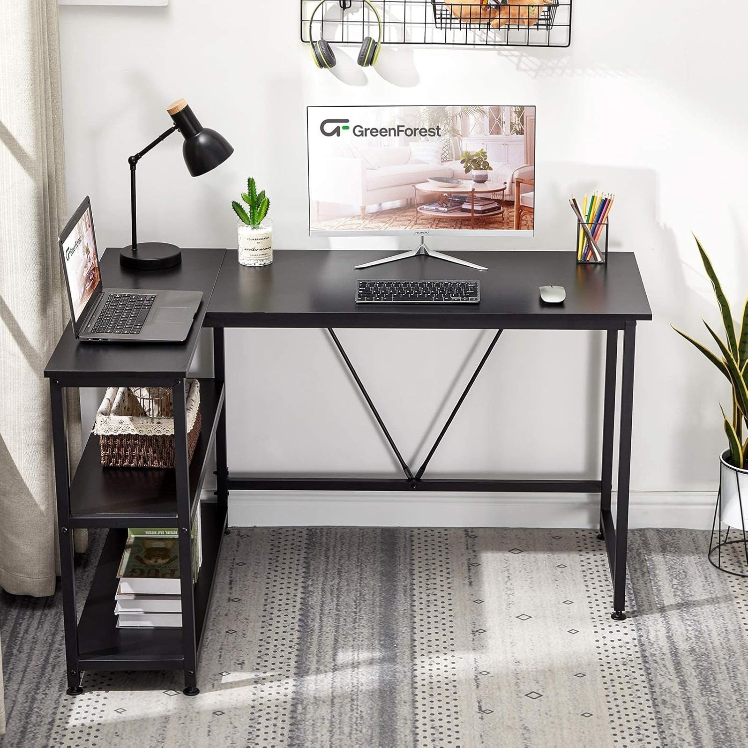 Black L shaped gaming desk with shelves featuring a laptop, monitor, desk lamp, and plant on top