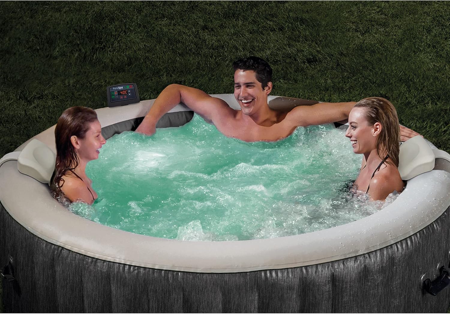 Three people relaxing in a craques outdoor inflatable hot tub with bubbling water on grass