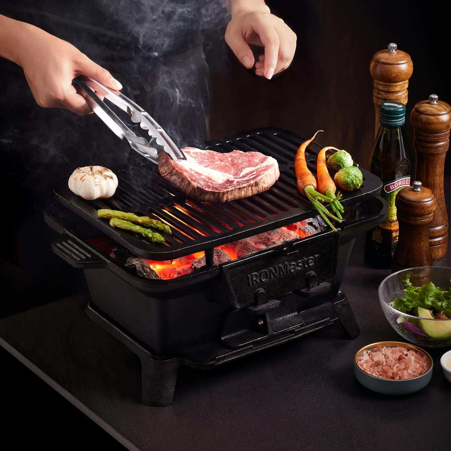 Craques portable cast iron bbq grill with steak and vegetables cooking over hot coals