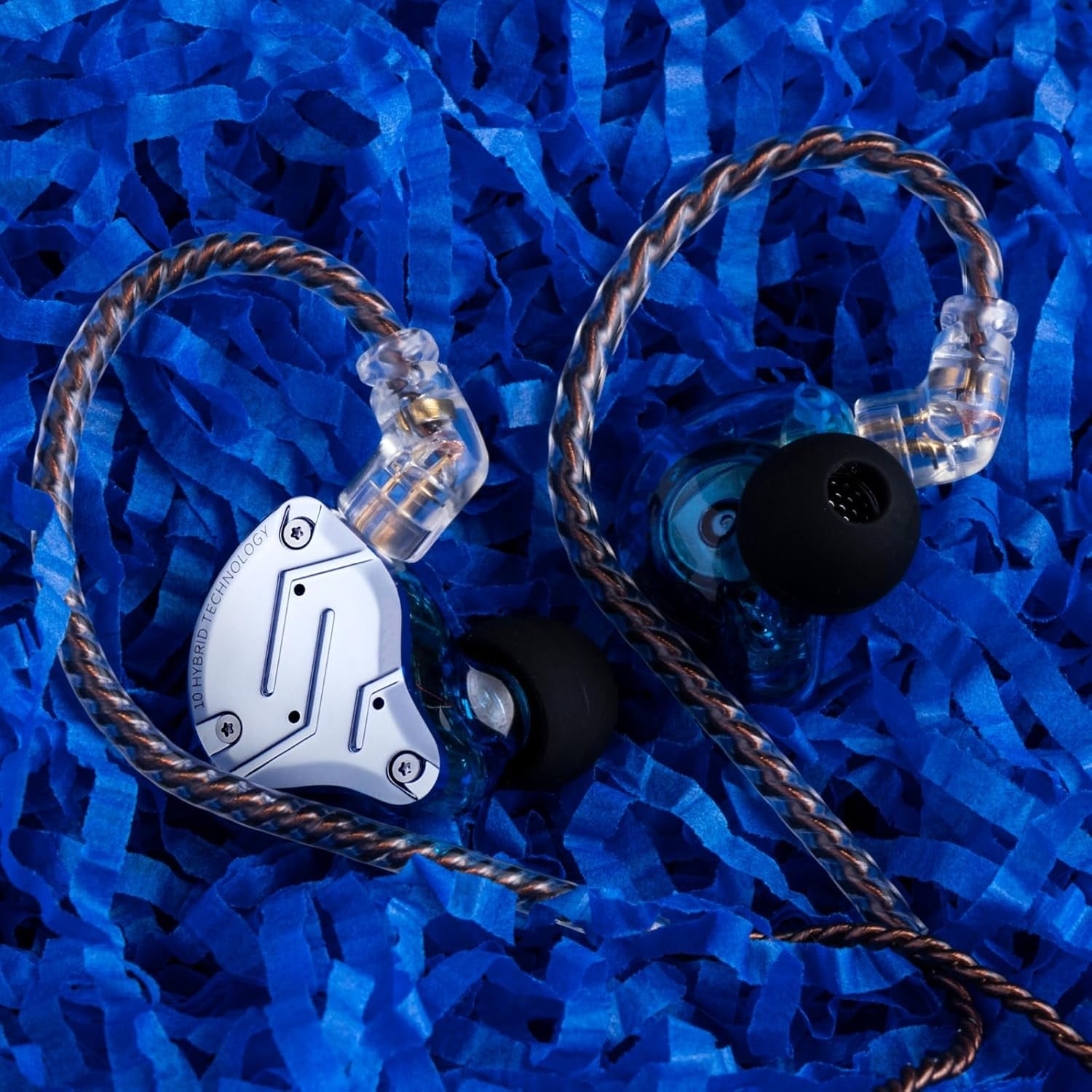 Craques hybrid in ear monitors for musicians with braided cables and clear earpieces on blue shredded paper