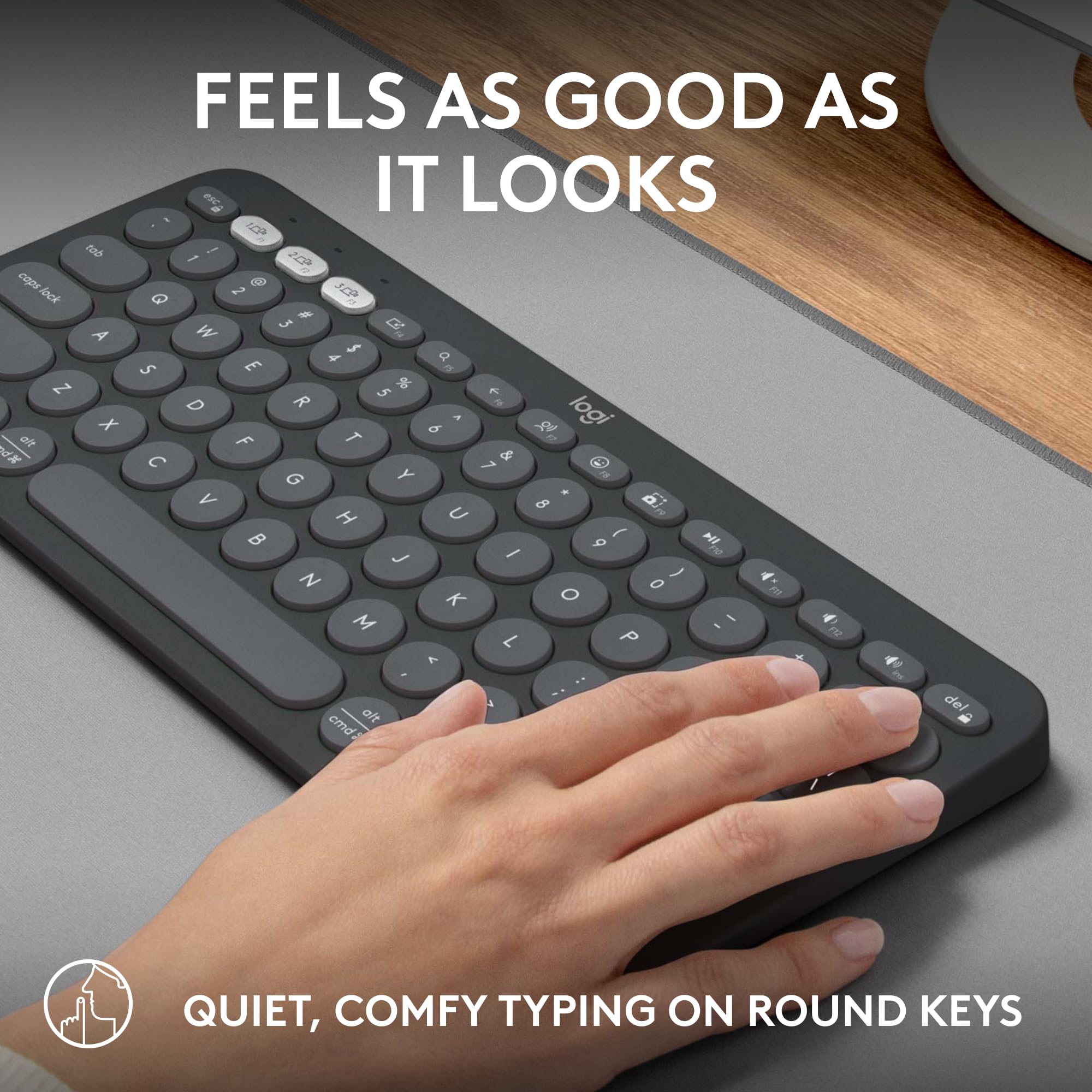 Logitech Pebble Keys 2 K380s wireless keyboard with round keys and a hand typing on gray desk mat