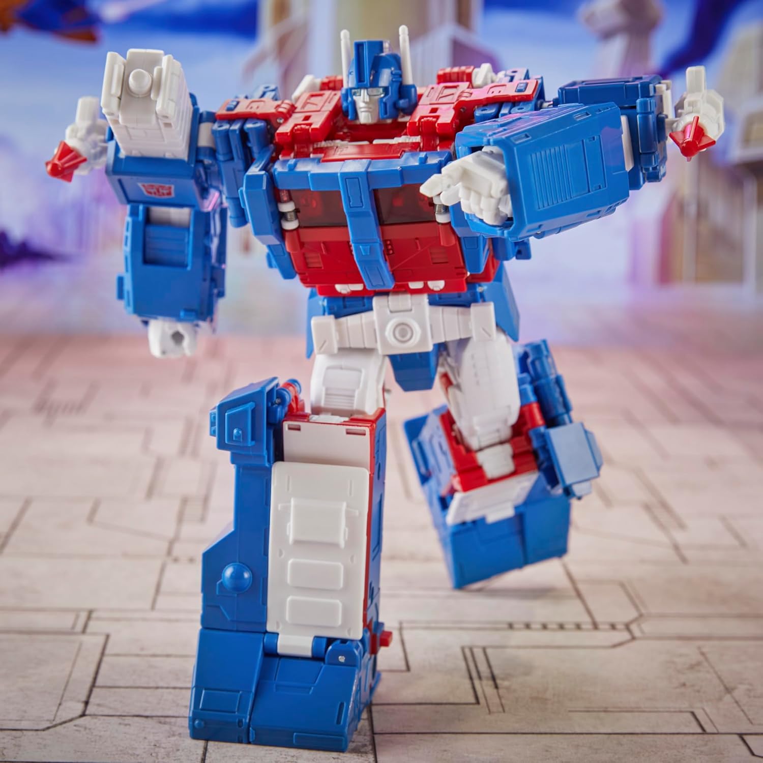 Transformers Ultra Magnus action figure in red white and blue colors posed dynamically on a city-themed background