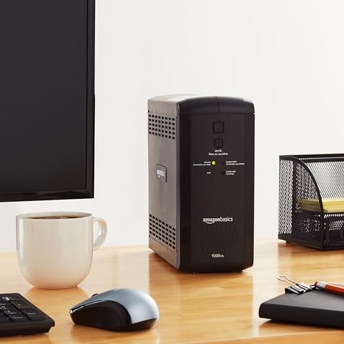 AmazonBasics line interactive UPS 1000VA on wooden desk near computer mouse keyboard and coffee cup