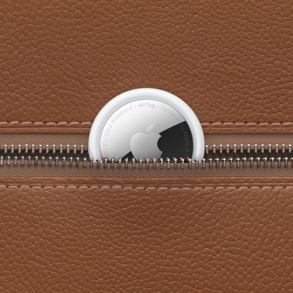 Apple AirTag single pack placed inside the brown leather zippered pocket for tracking items