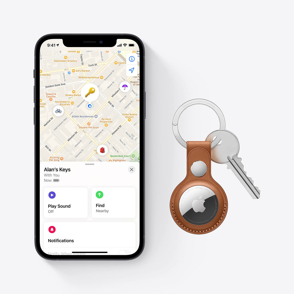 Apple AirTag single pack attached to keys with brown leather keychain and iPhone showing Find My app