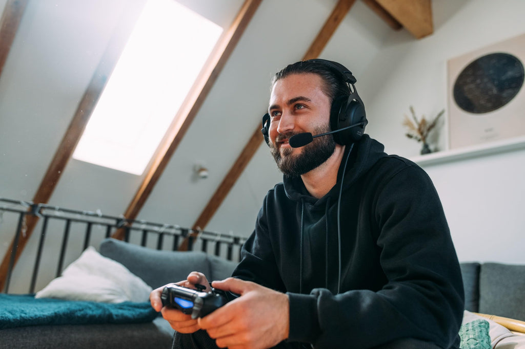Man wearing beyerdynamic MMX 300 PRO gaming headset playing video games with a controller in a cozy living room