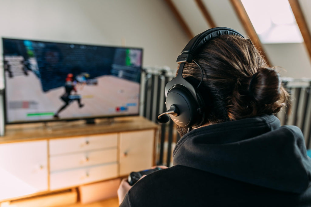 Person wearing beyerdynamic MMX 300 PRO gaming headset playing video games on a TV screen