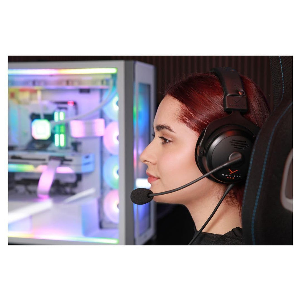 Gamer wearing beyerdynamic MMX 300 PRO gaming headset with microphone near RGB-lit gaming PC