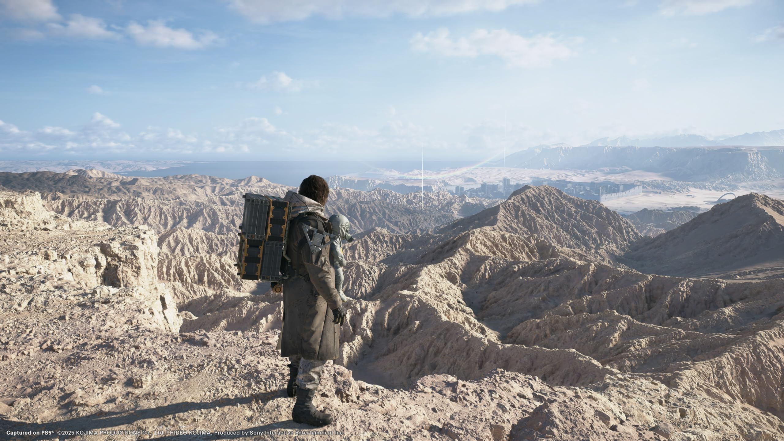 Scenic in-game landscape from Death Stranding 2 Collector's Edition PS5 showing character overlooking rocky desert terrain