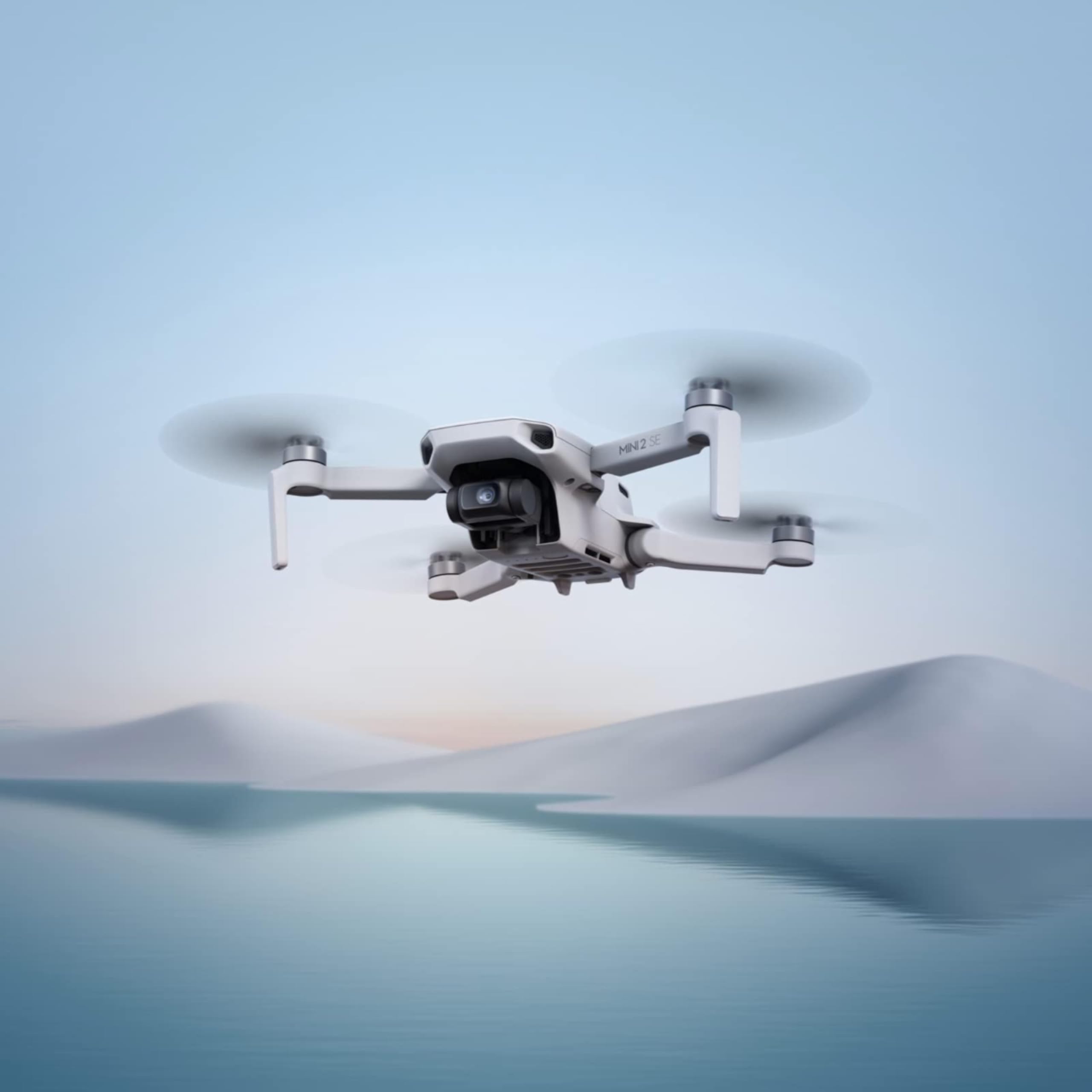 DJI Neo mini drone 4K UHD flying over calm water with distant hills in soft morning light