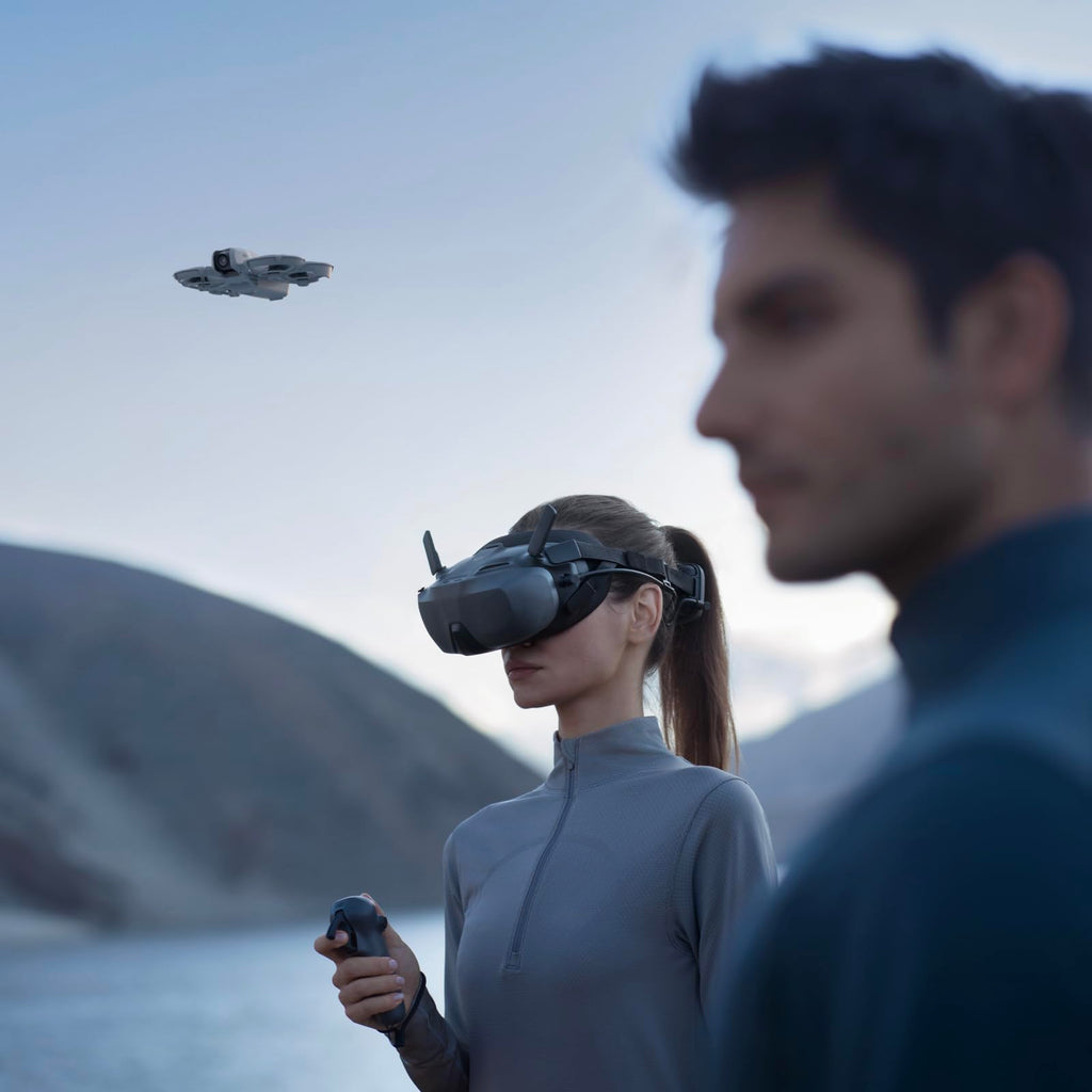 Woman using VR headset and remote to control DJI Neo mini drone 4K UHD flying outdoors near lake