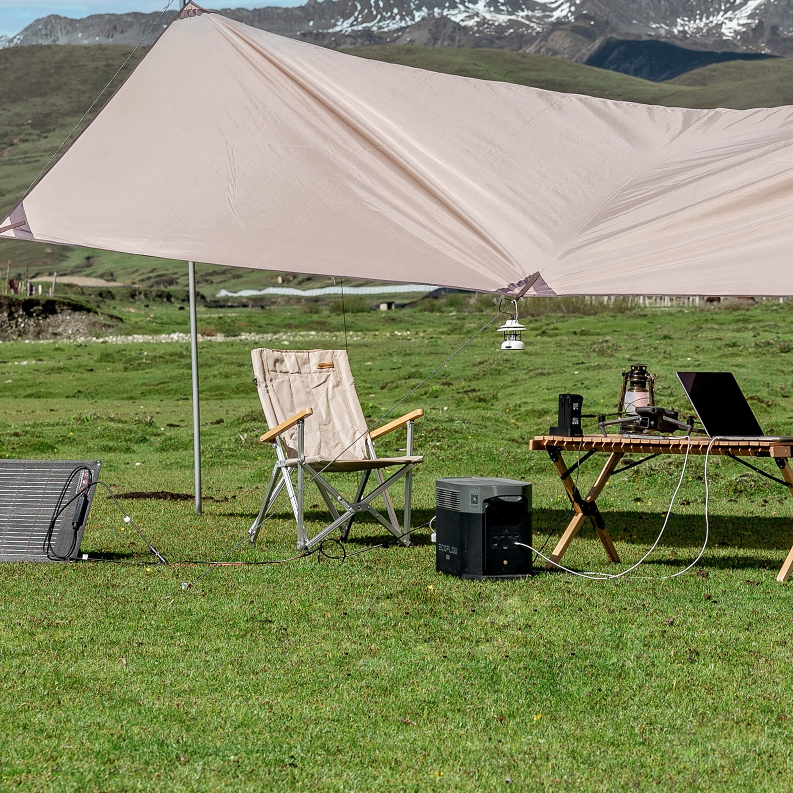 Craques portable solar generator kit powering laptop and lantern under camping tarp in mountain field