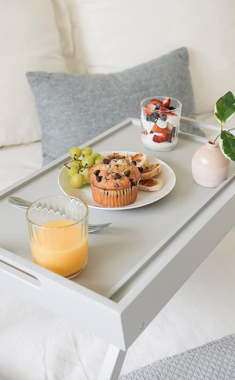 Extra large wood bed tray by craques holding breakfast with muffin, orange juice, grapes, and fruit parfait on a bed