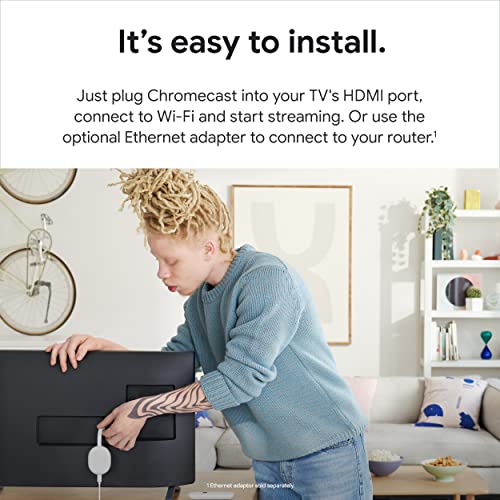 Person installing a 4K Google TV streaming device on the back of a TV in a cozy living room