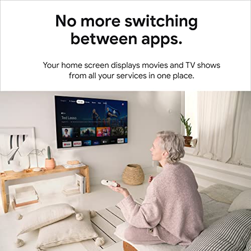 Older woman using 4K Google TV streaming device to watch Ted Lasso on a wall-mounted TV in a cozy living room