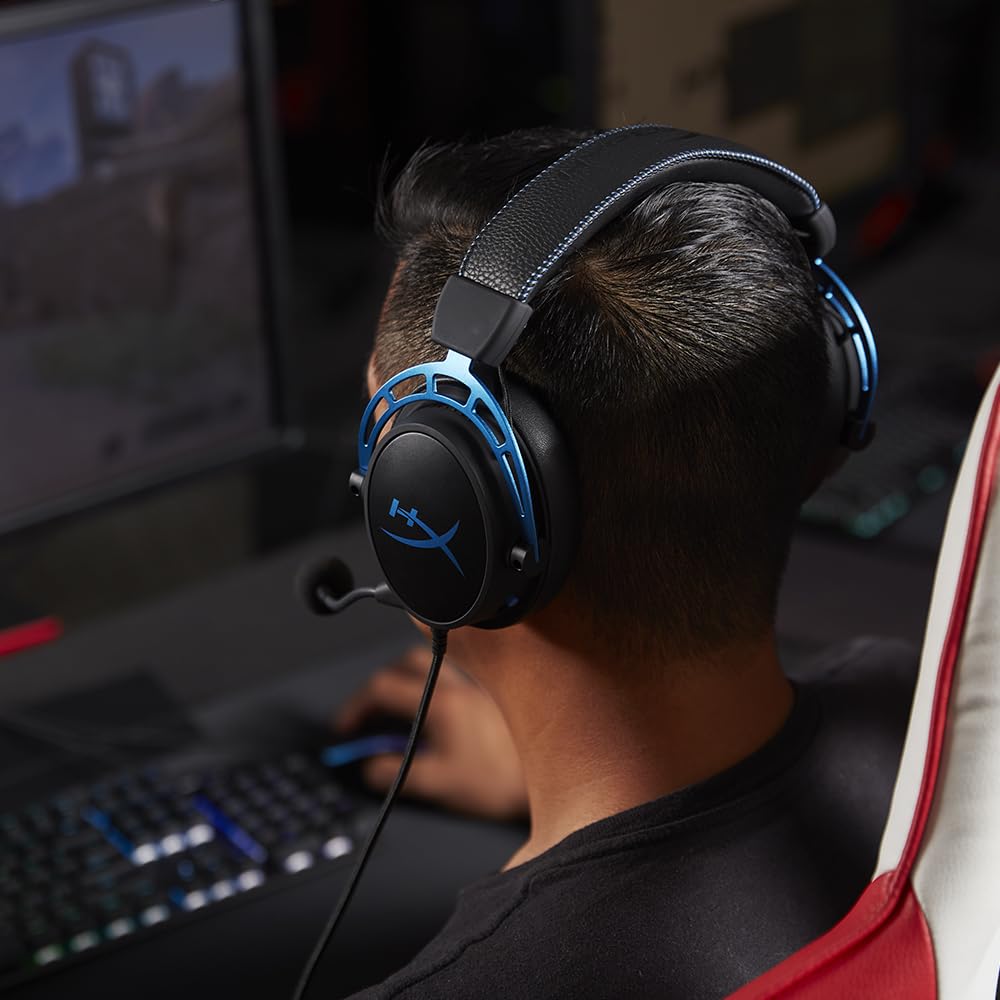 Person wearing HyperX Cloud Alpha gaming headset with blue accents while using a computer