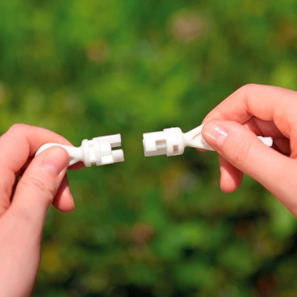 Hands connecting white plastic pieces for assembling an inflatable river float for adults