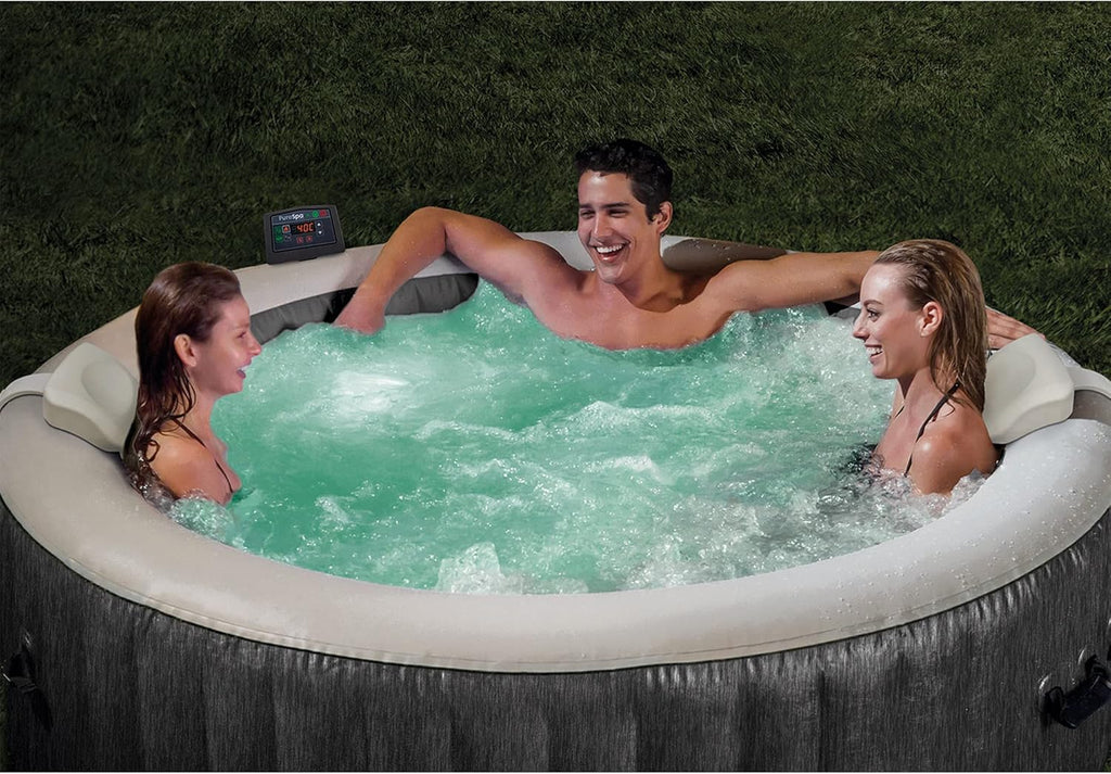 Three people relaxing in a craques outdoor inflatable hot tub with bubbling water on grass
