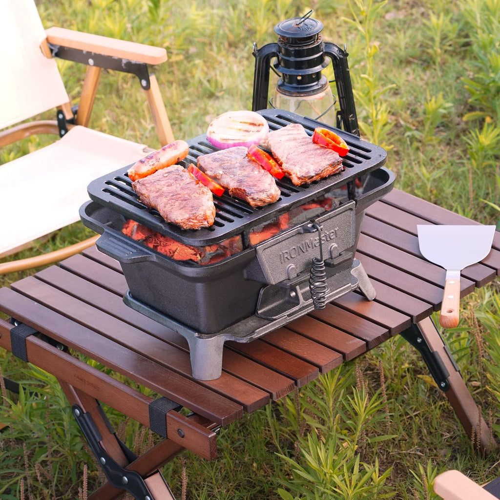 Craques portable cast iron bbq grill cooking steaks and vegetables on a wooden outdoor table
