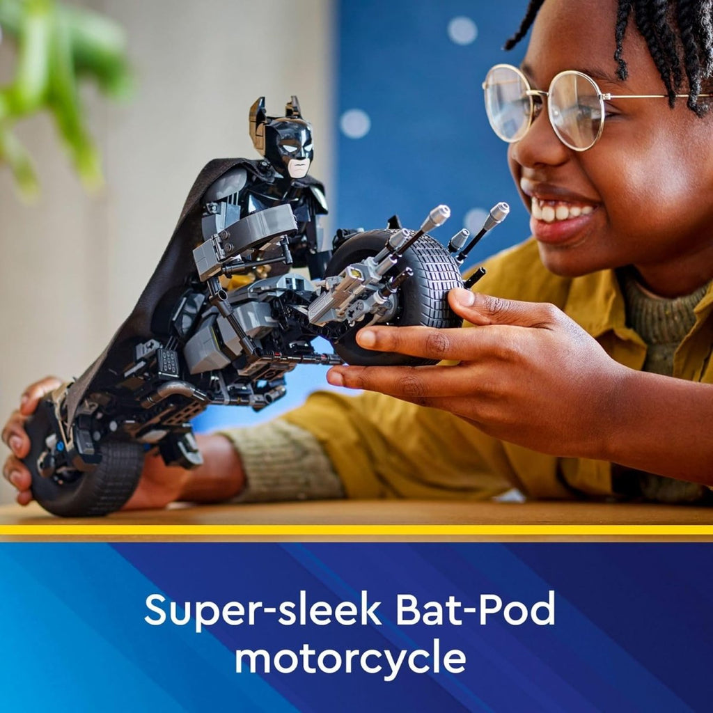 Child holding and smiling at LEGO Batman Bat-Pod bike set with detailed black Bat-Pod motorcycle
