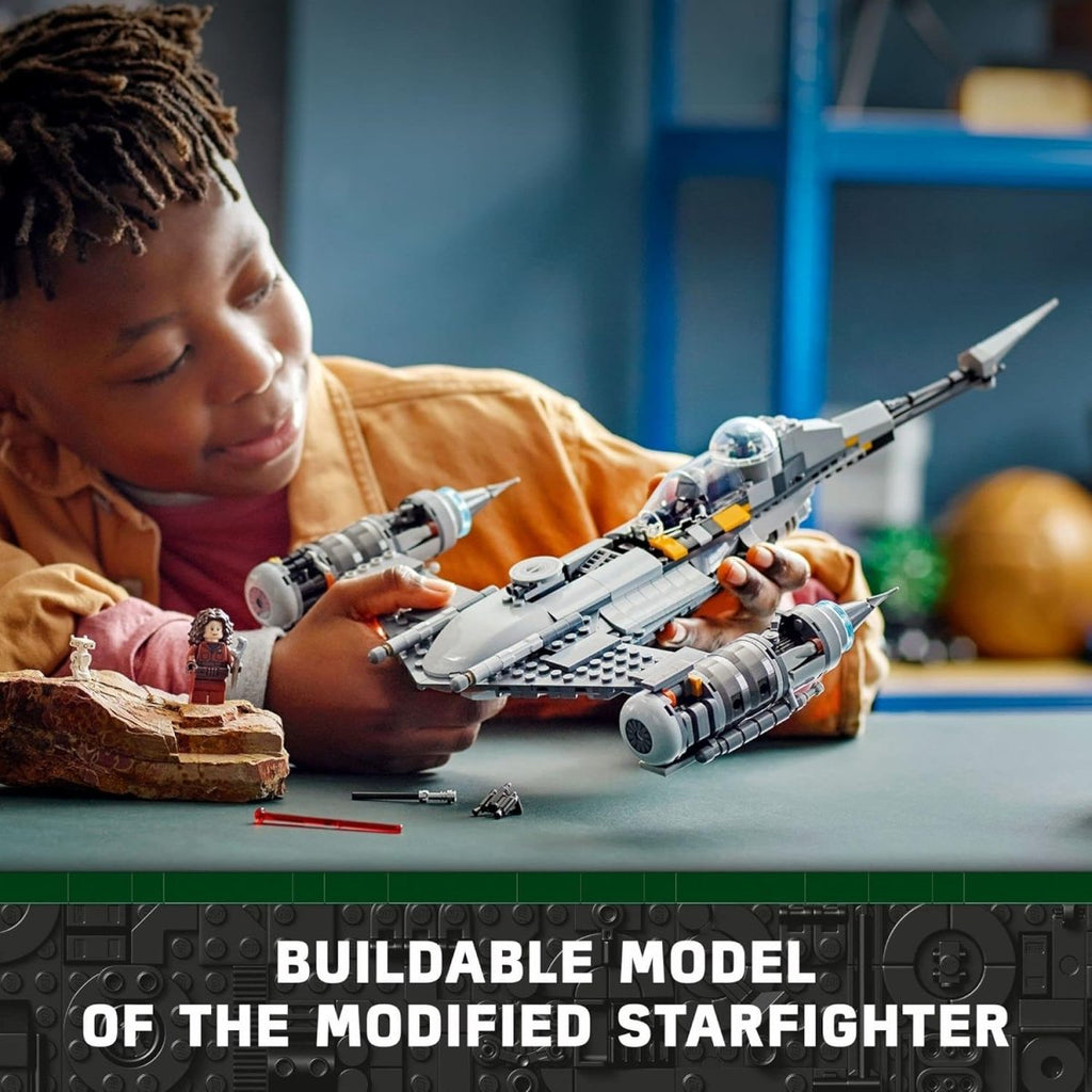 Child holding LEGO Star Wars N-1 Starfighter set buildable model with minifigure on table