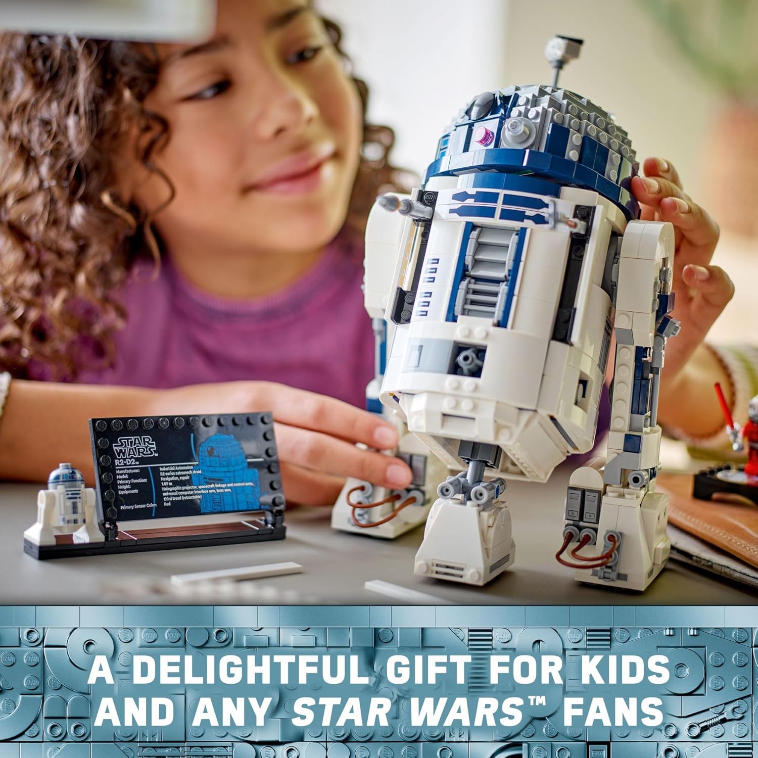 Child assembling LEGO Star Wars R2-D2 set with detailed droid model and information plaque