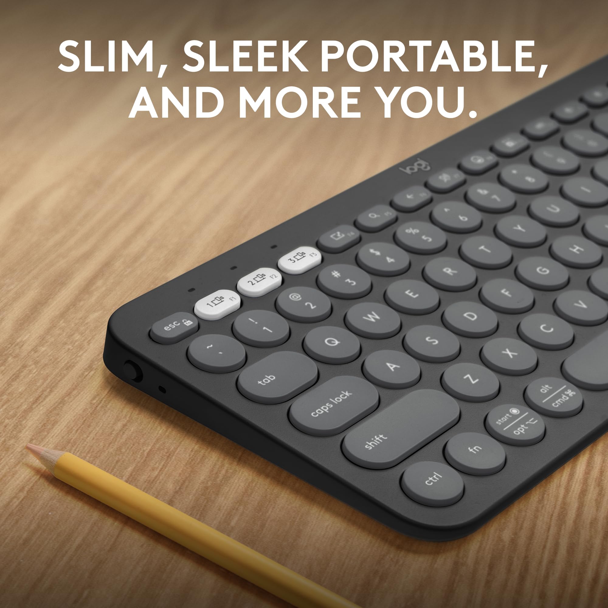 Close-up of black Logitech Pebble Keys 2 K380s wireless keyboard with round keys on wooden desk