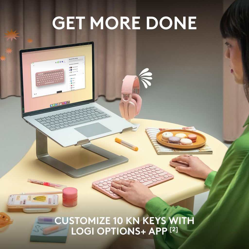 Person using Logitech Pebble Keys 2 K380s wireless keyboard in pink at desk with laptop on stand and snacks