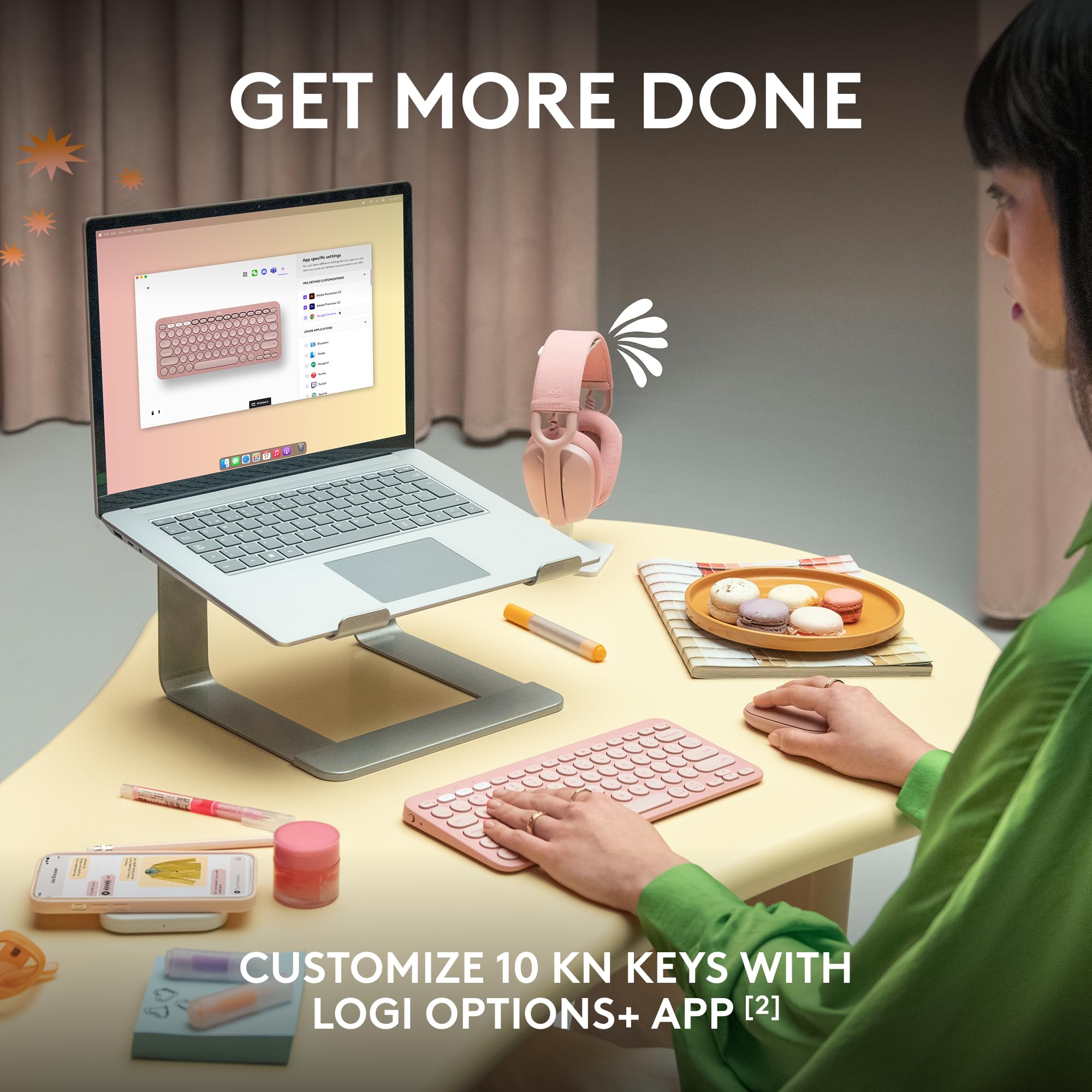Person using Logitech Pebble Keys 2 K380s wireless keyboard in pink at desk with laptop on stand and snacks