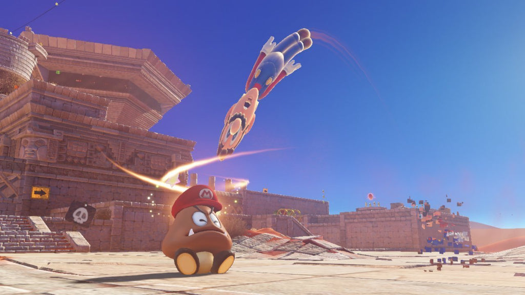 Super Mario jumping over a Goomba in a desert level of Super Mario Odyssey Nintendo Switch game