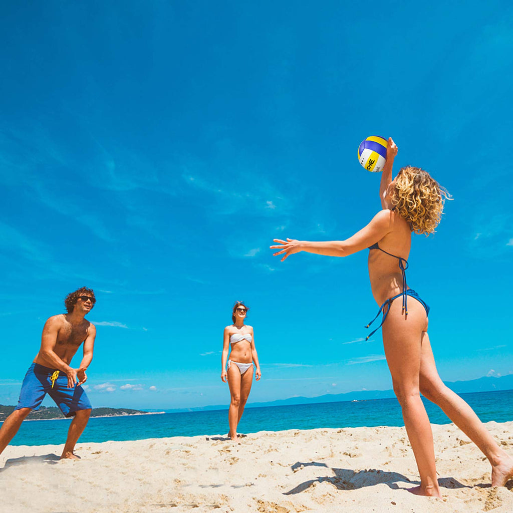 Three people playing beach volleyball with an official size 5 volleyball under clear blue sky
