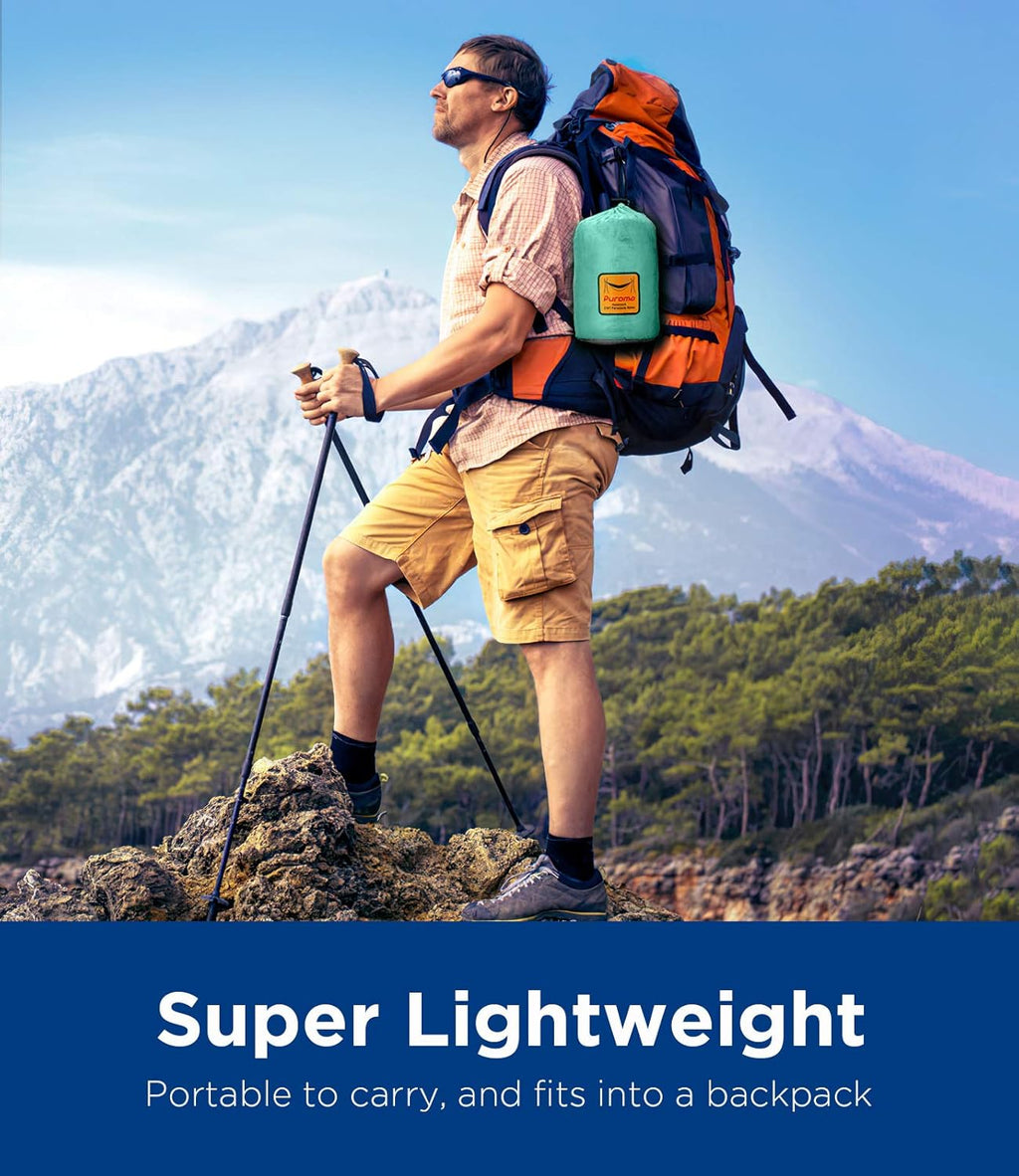 Hiker carrying an ultralight camping hammock packed in a green bag attached to a large backpack in mountain scenery