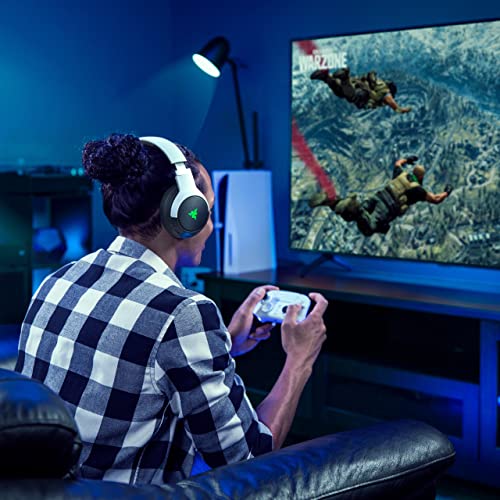 Person playing video games using Razer Wolverine V2 Pro PS5 controller with headset in a dimly lit room