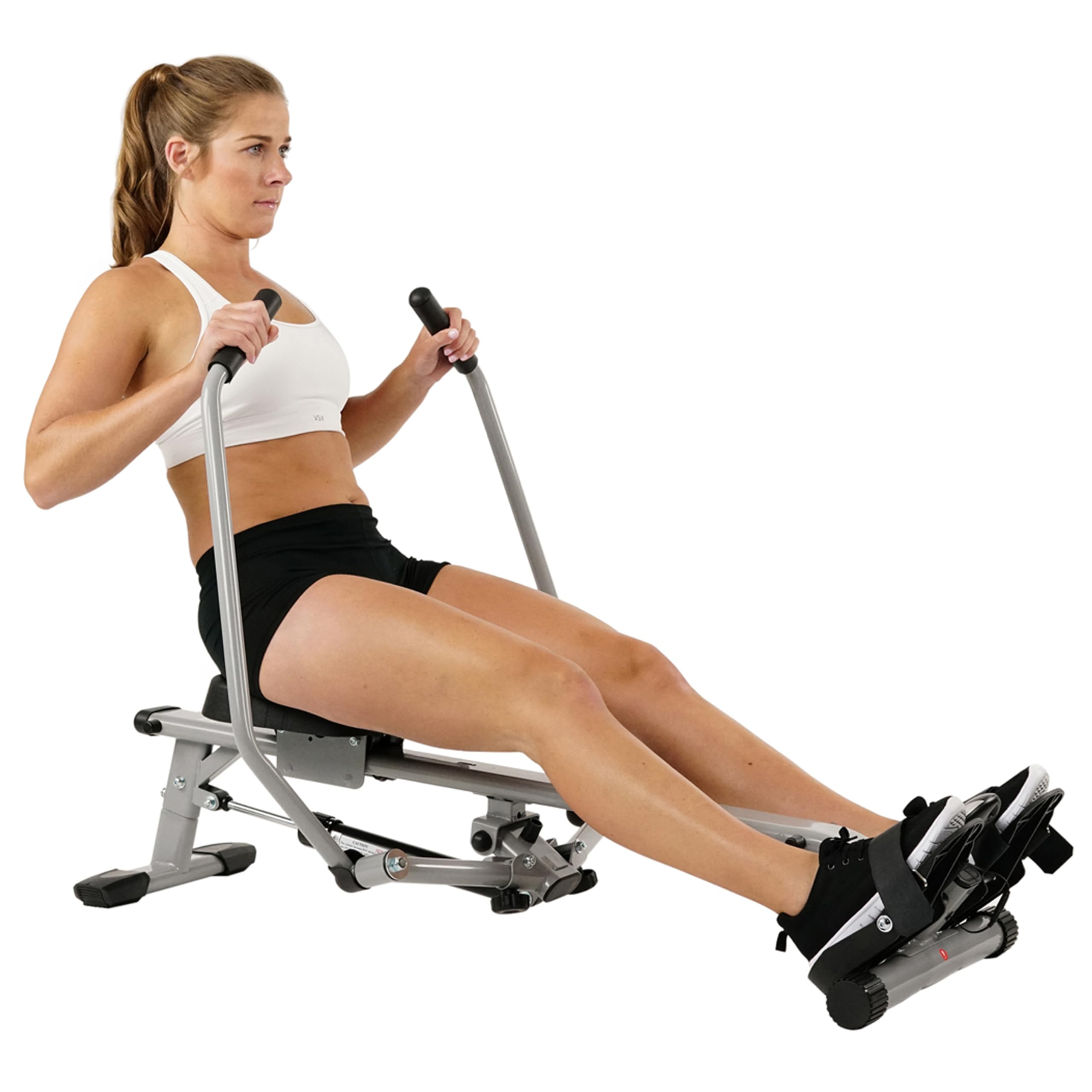 Woman using a compact rowing machine for home gym workout in black shorts and white sports bra