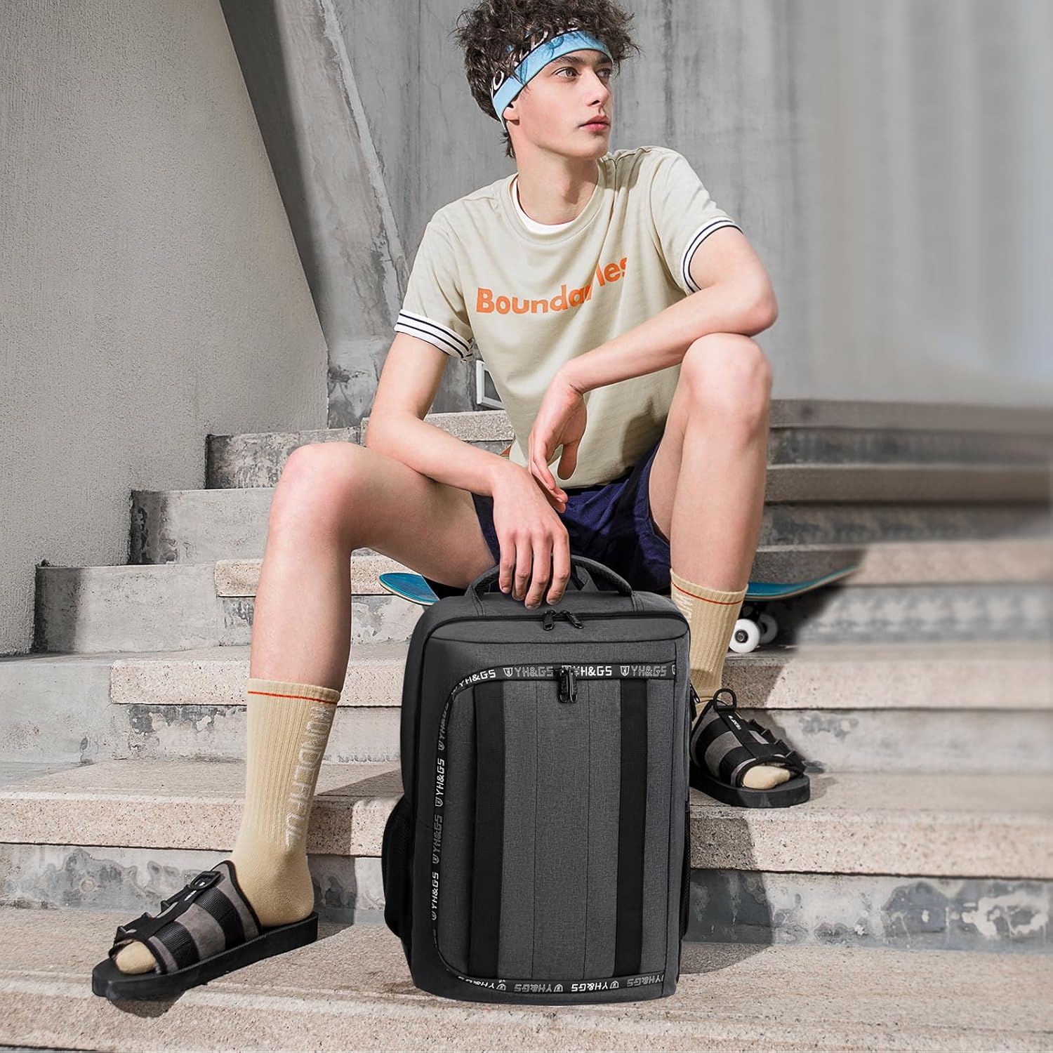 Craques travel backpack for PS5 in black carried by young man sitting on concrete stairs