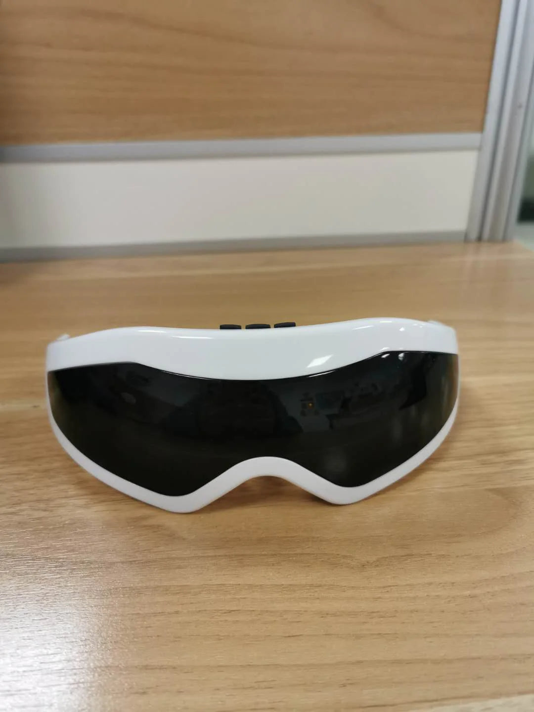 Craques VisionEase eye massager in white and black with ergonomic design on wooden surface