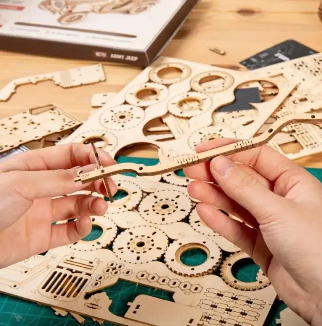Hands assembling pieces from craques 3D wooden puzzle train kit with laser-cut wooden parts on table